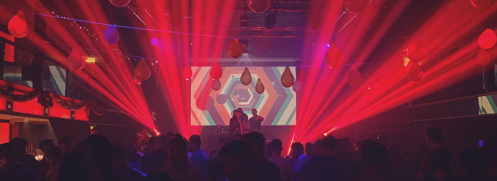 Red beam lighting over a packed crowd at Elements New Year's Eve