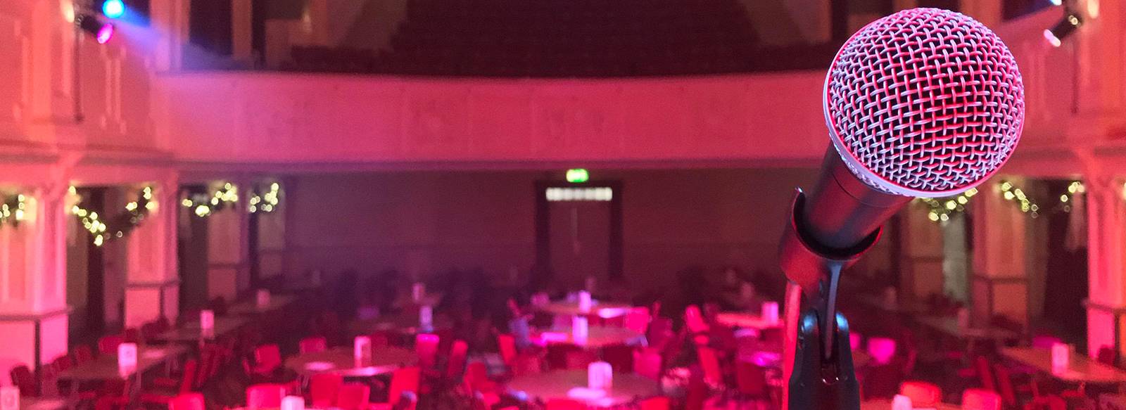 A microphone on stage looking out over a hall set for an event